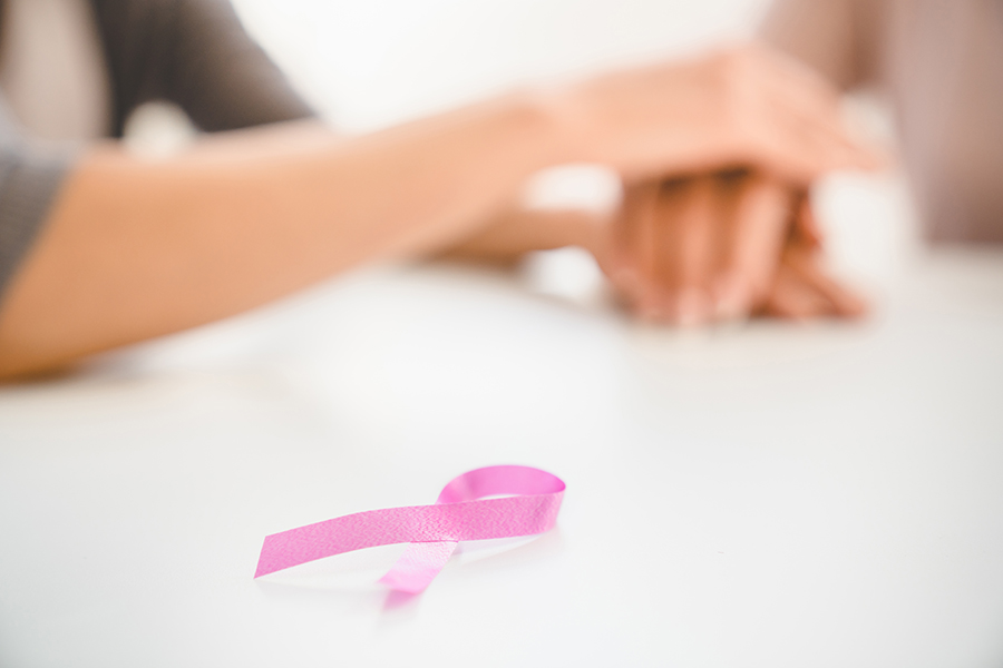 Pink ribbon against breast cancer with supporting women`s hands. Fighting tumors, oncology recovery.